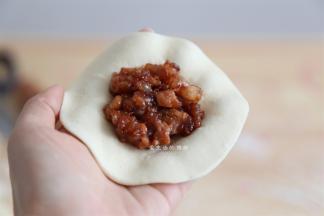 取一个面团，擀成中间厚旁边略薄的面片，放上适量的馅料，包起来，褶子捏得好看更有食欲哦！
