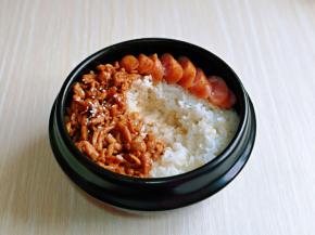 肉丝放入米饭的一侧，撒上熟白芝麻，香肠切片摆盘。