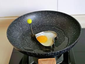 起油锅，放一个爱心模型，磕入鸡蛋，小火煎熟盛出备用。