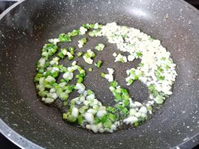 锅里加油下葱花与蒜末炒香。