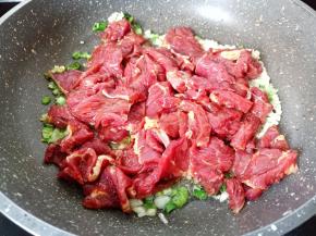 把腌制好的牛肉放入锅里，用铲快速将牛肉炒散。