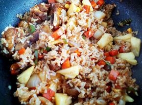 八成熟时下入米饭，翻炒至米粒充分吸收油脂，下入菜菠萝丁一起翻炒两分钟，加入盐、糖、鸡精调味，即可关火盛出。