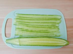 黄瓜对半切开，用削皮刀削成长长的薄片。