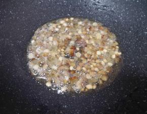 锅里不用放油，直接放入切好的腊肉丁，小火翻炒至腊肉的油脂流出，肉丁变至透明状。