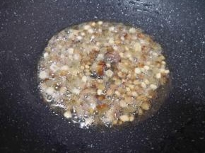 锅里不用放油，直接放入切好的腊肉丁，小火翻炒至腊肉的油脂流出，肉丁变至透明状。