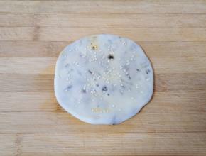 收口朝下，撒上少许熟白芝麻，用擀面杖擀成薄饼，依次做好剩下的面团。
烤箱上下管200度预热。