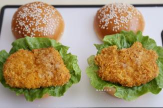 接着将猪排和洗好的剩菜放在汉堡胚上，挤上适量的沙拉酱或千岛酱。