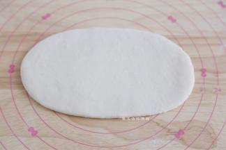 取出松弛好的面团，取一个，擀成长舌状，看到有气泡的地方要拍走气泡哦。