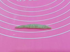 取一块小面团，放手掌心来回搓成两头尖的长条，如图。