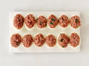 取适量将调好的肉馅盖在鸡蛋上，稍微按压粘紧。