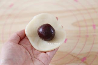 将卷子轻轻地擀成中间略厚的圆形，放上蛋黄豆沙馅。