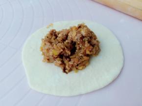 取一个面团擀成两边薄中间厚，加上肉馅包起来。