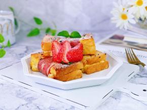 取出烤好的三明治，筛入耐高温糖粉，再装饰上草莓。