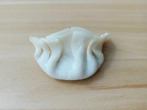 将饺子皮放上一勺馅包起来。