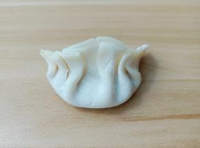 将饺子皮放上一勺馅包起来。