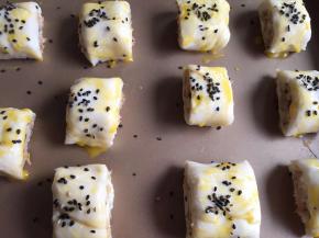 摆入烤盘，表面刷少许蛋黄液，撒黑芝麻做装饰