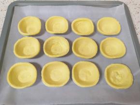 烤盘里铺上油纸，放上解冻的蛋挞皮。