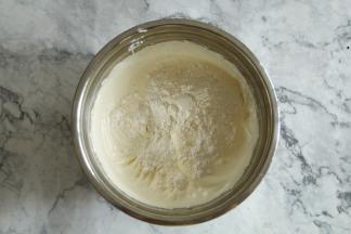 然后筛入低筋面粉（最好提前过筛好），不要倒在一个地方，尽量分布均匀，防止压消泡。、然后用刮刀切拌、翻拌均匀。二点钟方向切入到7点钟方向，从盆边翻起到盆中心，动作尽量轻柔快速的翻拌到无干粉颗粒。