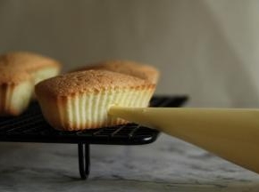 裱花袋剪小口，放入孔洞中，慢慢挤入奶油霜，不要一下子挤得太多，不然蛋糕体膨胀太多会爆开。