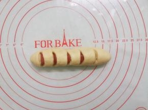 用剪刀斜着剪几下，香肠要剪断，但底部面团不剪断