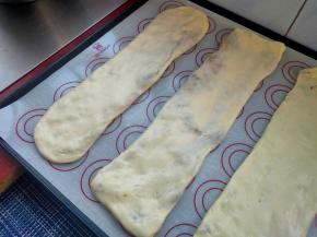 在手里轻轻压扁，转移到烤盘上，压扯成长方形，饼的长度压成烤盘的宽度即可，再在表面撒上少许白芝麻，轻轻压一下。（饼皮在压的过程中不小心裂开也是没有关系，不影响口感）