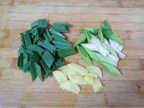 蒜苗叶子和茎部分开切成段，生姜切成片。
