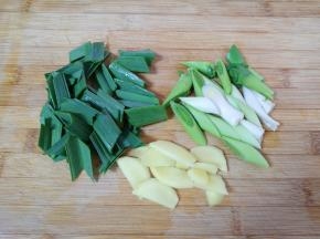 蒜苗叶子和茎部分开切成段，生姜切成片。
