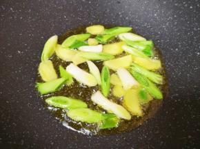 炒锅内倒适量的食用油烧热，下入蒜苗茎部和生姜片爆香。