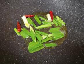 锅底留余油，下入蒜苗和干红辣椒炒香。