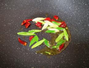 炒锅内倒适量的食用油烧热，下入蒜苗和干红辣椒爆香。