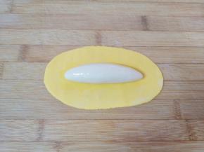 黄色的面皮中间部分刷上一层玉米油，放上白色的长条状面团，然后用刷子给白色的面团刷上一层玉米油，如图。