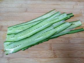 黄瓜洗干净，用削皮器从黄瓜的一头刮起，注意用力均匀，将黄瓜刮成薄薄的长条状。