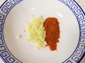 大蒜切成碎末放在碗里，加入一勺辣椒面搅拌均匀。
