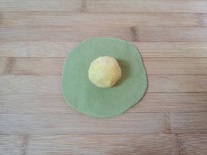 取一个绿色的面团擀开，放上一个豆沙馅。