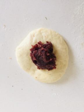 取一个小剂子，沾少许面粉揉圆按扁，放入适量的豆沙馅儿！