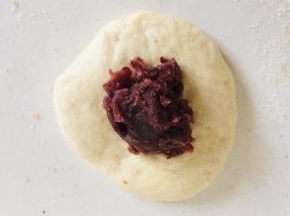 取一个小剂子，沾少许面粉揉圆按扁，放入适量的豆沙馅儿！