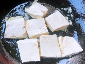 锅中倒入油加热放入豆腐中火煎起来