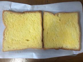 两片吐司摆在铺有油纸的烤盘上，刷上鸡蛋液。