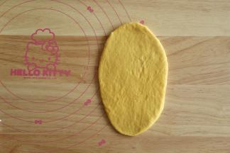 取一个松弛好的面团，拍一点点高粉防粘，按扁，用擀面杖擀干成椭圆形。