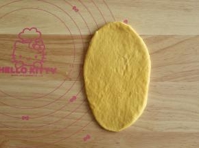 取一个松弛好的面团，拍一点点高粉防粘，按扁，用擀面杖擀干成椭圆形。