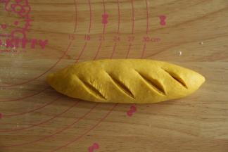 收口朝下，双手略微搓揉面包胚，整理成橄榄型。割包刀割口，想要烤完让馅料露出来，就要割深一些露出馅料。