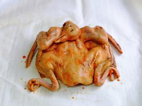 取出腌制好的乳鸽，用食品剪刀把肚子剪开，放在油纸上，如图。