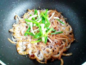 炒干水分后转小火，把鱼干煎酥脆，放入小葱翻炒出香味，关火出锅。这步注意火候。