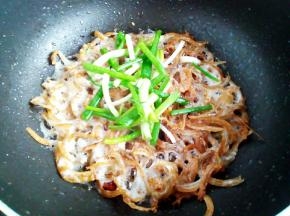 炒干水分后转小火，把鱼干煎酥脆，放入小葱翻炒出香味，关火出锅。这步注意火候。