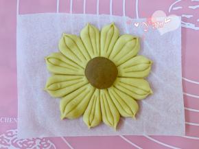 取一个棕色面团滚圆，擀成小圆片放在中间。按印子切出12份，每瓣中间再印两刀，捏出花瓣即可。