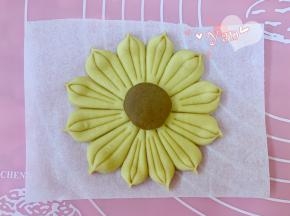 取一个棕色面团滚圆，擀成小圆片放在中间。按印子切出12份，每瓣中间再印两刀，捏出花瓣即可。