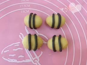 取两个小细条围在黄色椭圆形的面团上，盖保鲜膜备用。