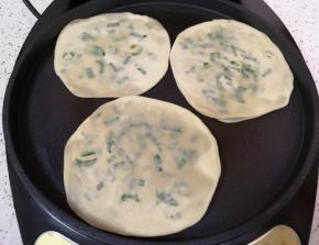 电饼铛预热，刷上一层菜籽油，放入做好的葱油饼，葱油饼上面也刷上一层菜籽油。