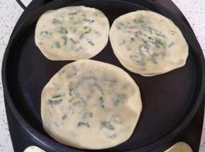 电饼铛预热，刷上一层菜籽油，放入做好的葱油饼，葱油饼上面也刷上一层菜籽油。