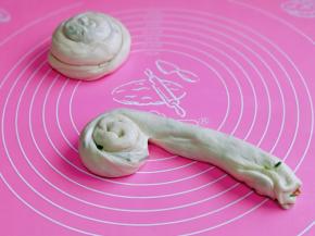 取一块醒发好的面团，慢慢抻长，从一端卷起，如图。
